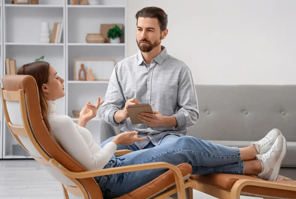 A practitioner listening and taking notes while a client sits comfortably and talks.