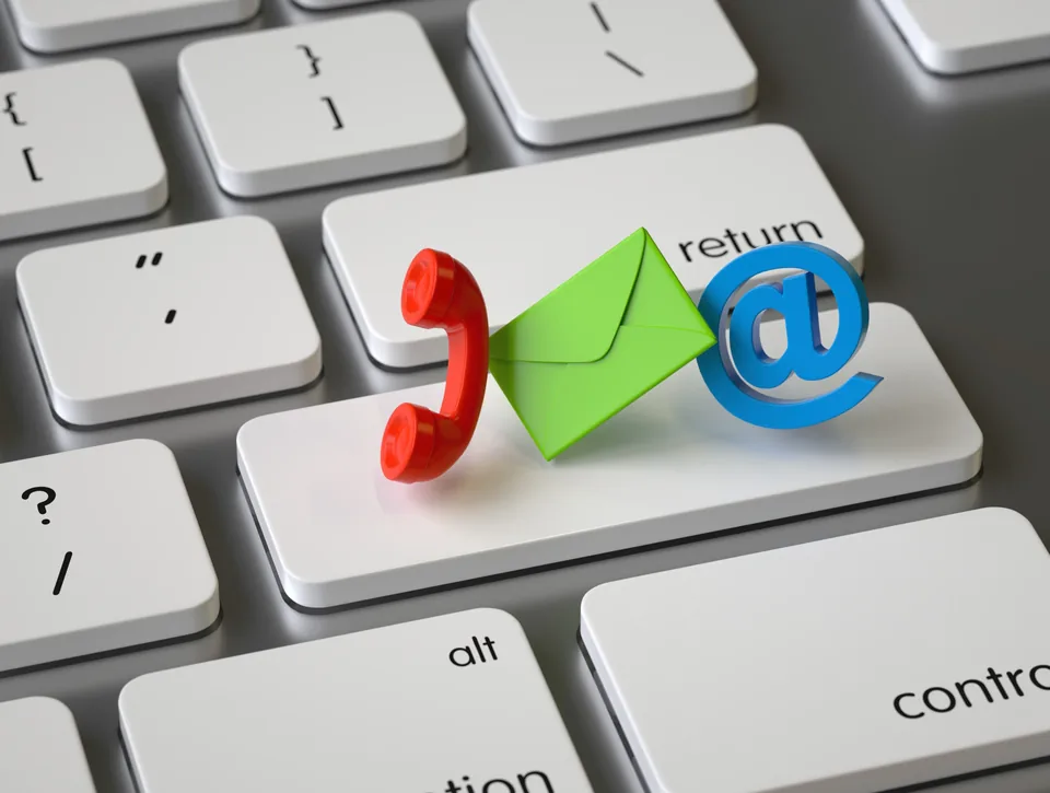 Illustrated telephone, envelope and at-sign icons resting on a computer keyboard, representing ways to get in touch.
